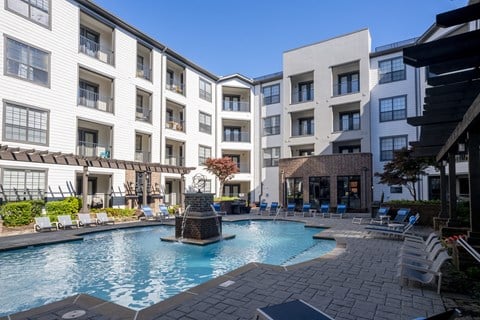 a swimming pool with a fountain in front of a white building